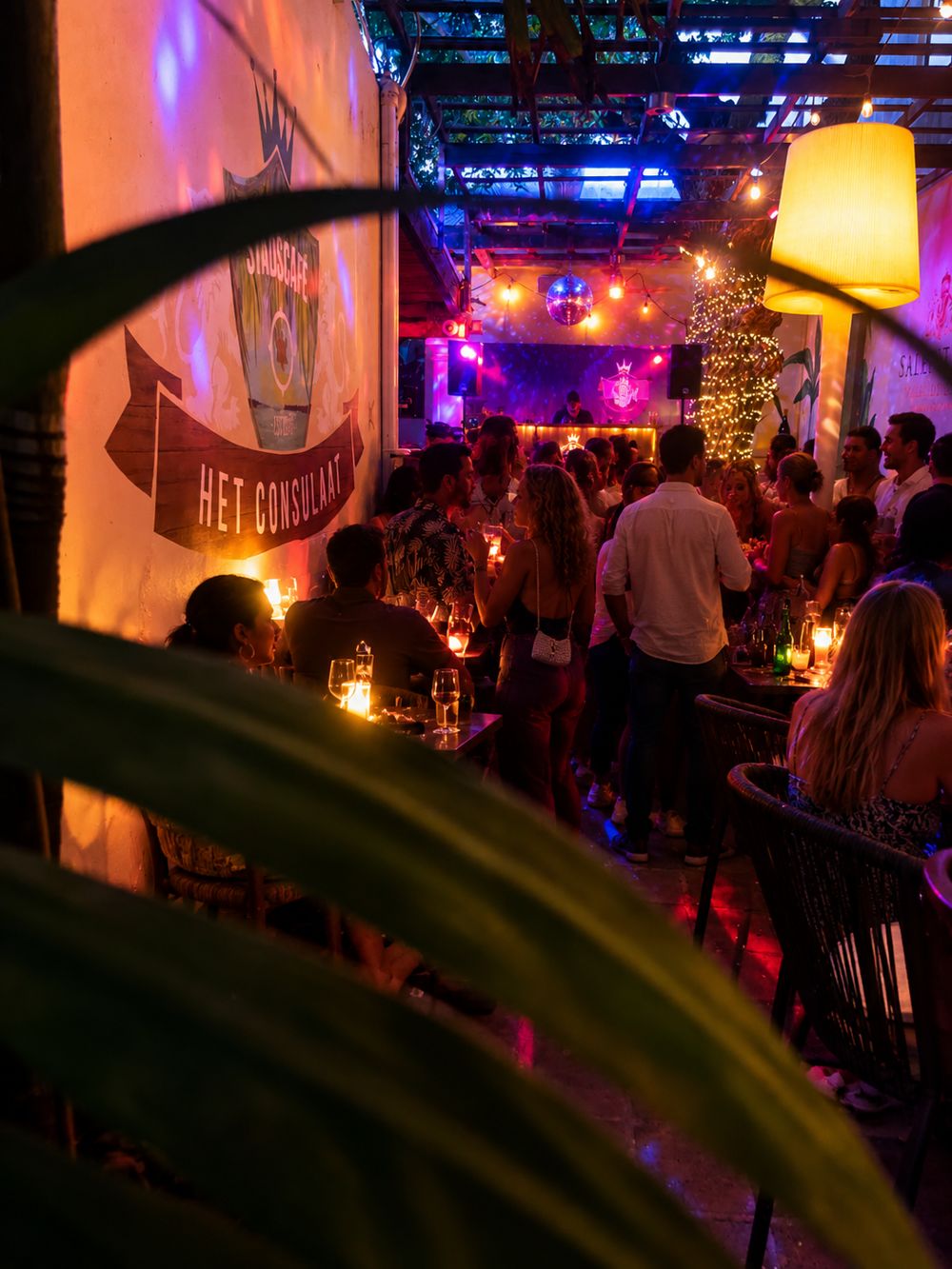 Volle tuin van Het Consulaat bij avond met lichtjes en dj-booth